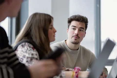 Students engaged in a small group discussion at emlyon, using laptops during a business course session.