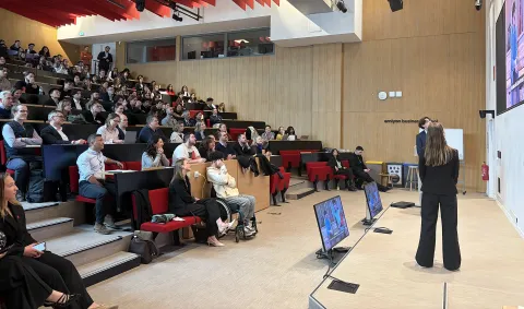 Intervenants sur scène dans l'amphithéâtre d'emlyon, devant un écran présentant des informations sur un investissement