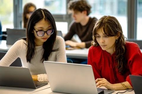 tudiants emlyon business school travaillant sur ordinateur portable en groupe dans une salle de cours