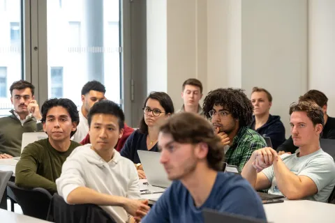 Group of students listening to a lecture with laptops in a business school classroom