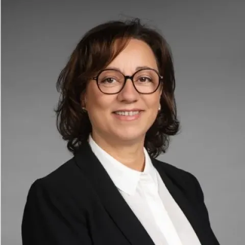 Portrait professionnel de Sabine Buis, souriante, en tailleur noir.