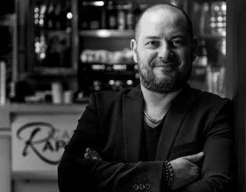 Portrait photographique en noir et blanc d’une personne cadrée en buste, portant une veste