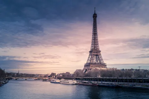 Vue de la tour Eiffel au coucher du soleil avec la Seine et des bateaux à Paris.