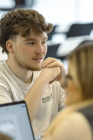 Étudiant participant à une séance de travail collaborative et échangeant avec ses pairs dans le cadre d’un programme de bachelor en management.