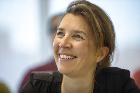 Professional portrait during a meeting or collaborative workplace discussion in an office environment.