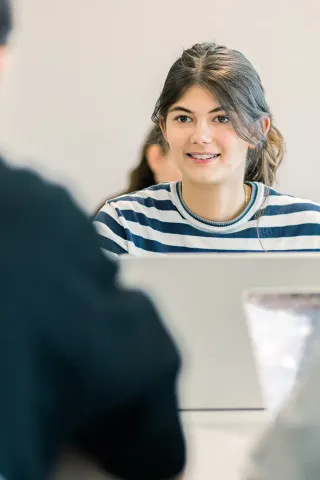 Student taking part in a classroom discussion in front of a laptop at a business school.