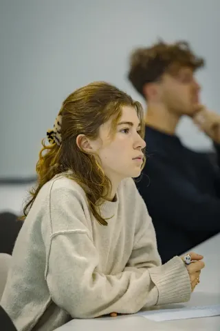 Étudiants en école de commerce participant à un cours en salle de classe moderne, travaillant sur des ordinateurs portables.