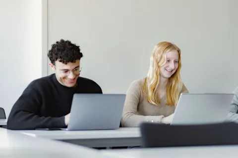 Students using laptops during a training session in a modern classroom environment.