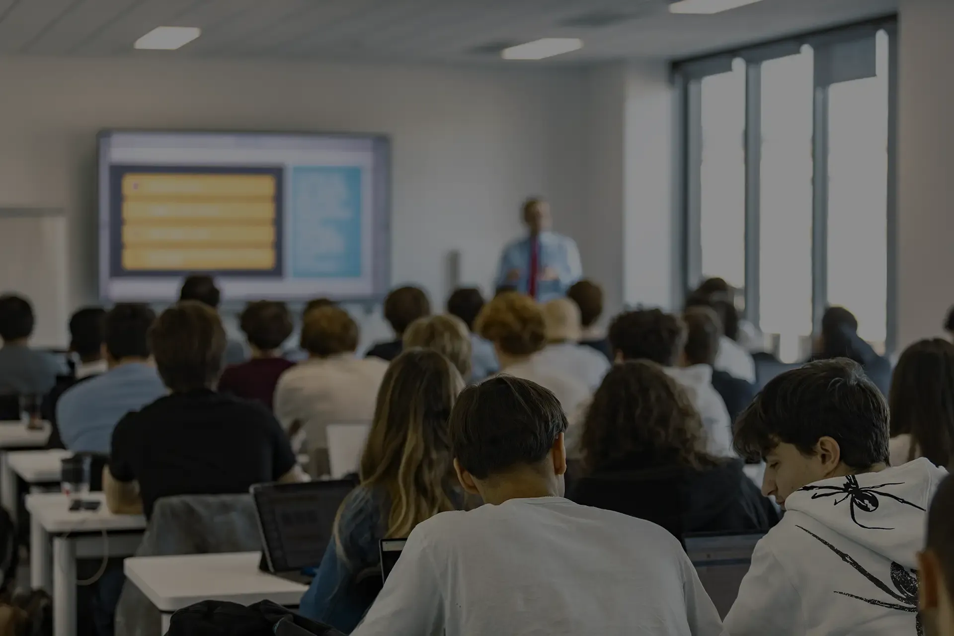 Conférence en salle de cours à emlyon tech school avec étudiants et présentation projetée.